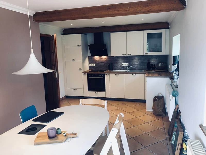 Helle Küche mit großem Esstisch und Zugang zum Garten